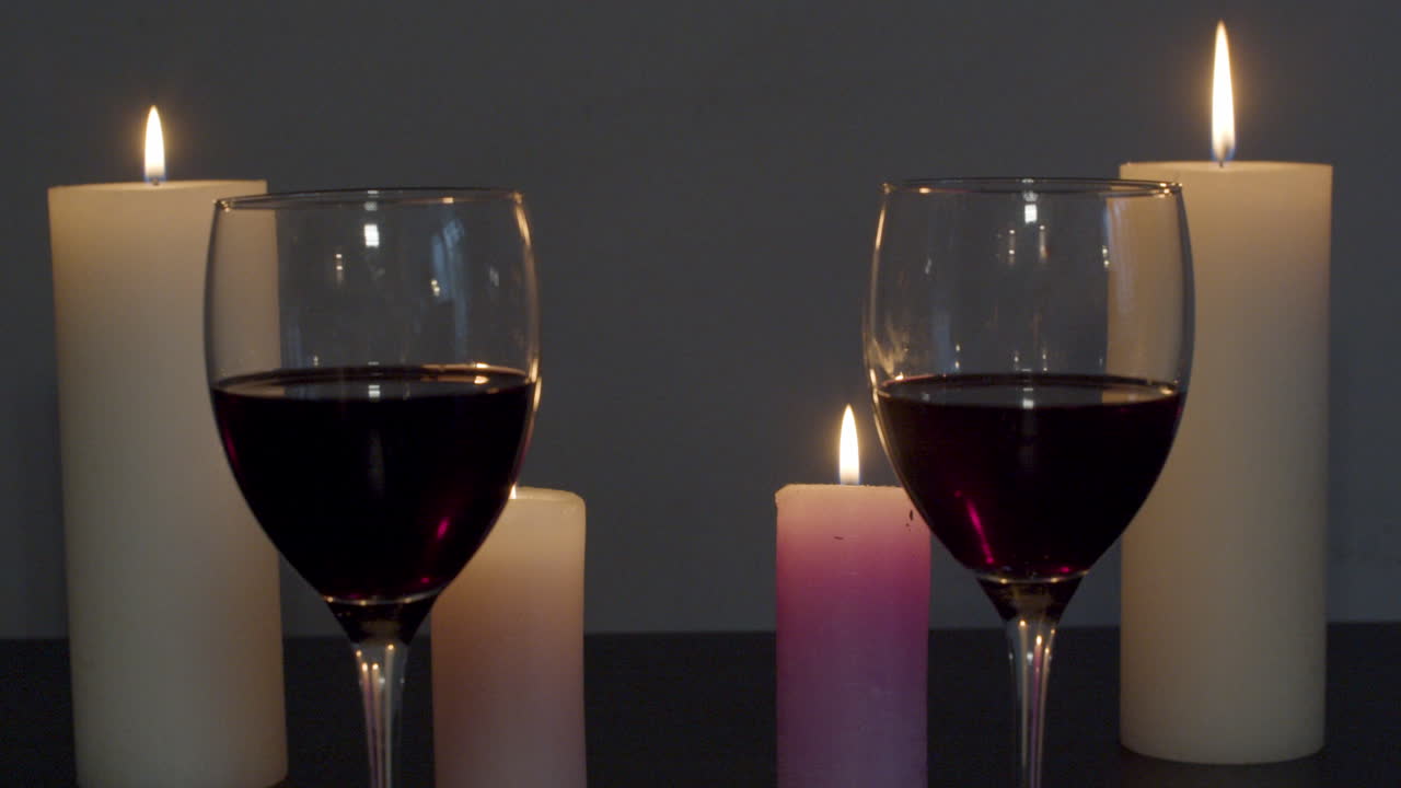 Dolly in of two glasses of wine on a candle lit table
