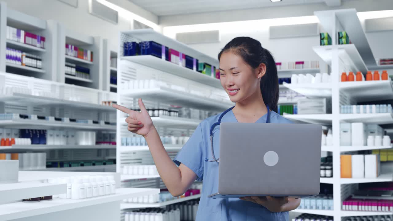 아시아 여성 의사는 스테토스코프를 들고 노트북을 들고, 을 가리키며 약국에서 미소 짓고 있습니다.