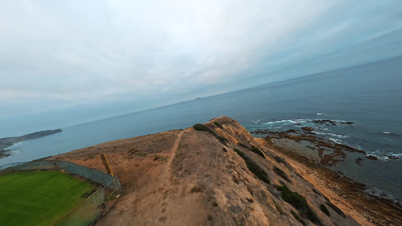 Volo in avanti sopra una scogliera rocciosa sulla costa marina che rivela una vista panoramica del mare e sorvola piattaforme rocciose che sporgono dalla superficie dell'acqua.