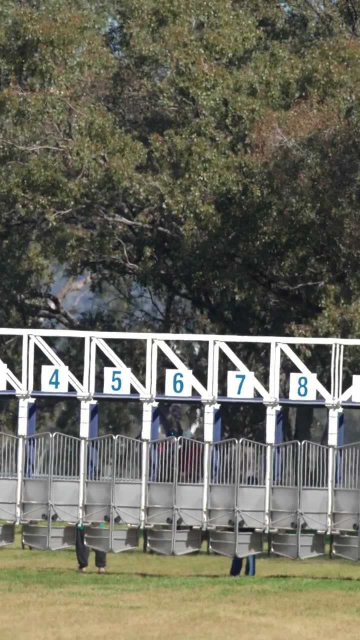 Panning shot of numbered starting barriers and emergency vehicles at a racetrack in Gunnedah, Australia.