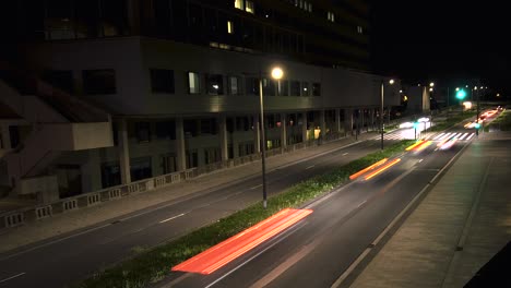 nighttime timelapse capturing the vivid trails of car lights moving in both directions along an urban street, highlighting the rhythmic flow of city traffic