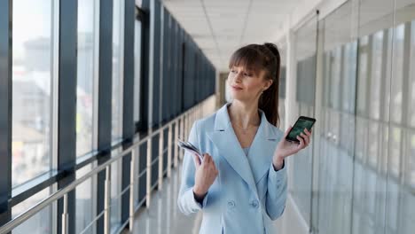 medium plan of young attractive girl in business suit showing smartphone and bundle of money