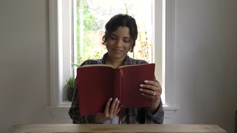 Happy-Puerto-Rican-girl-reading-holy-bible-at-home-backlit-from-window