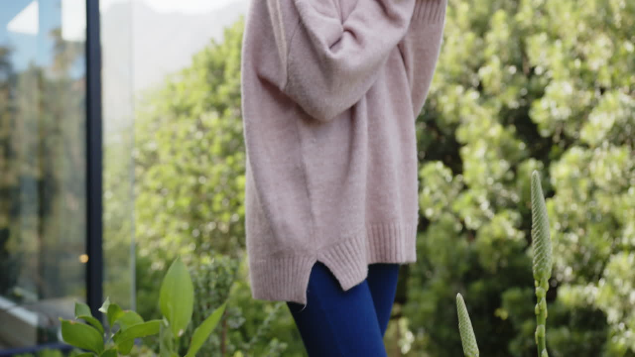Holding cup, woman enjoying outdoor relaxation in cozy sweater