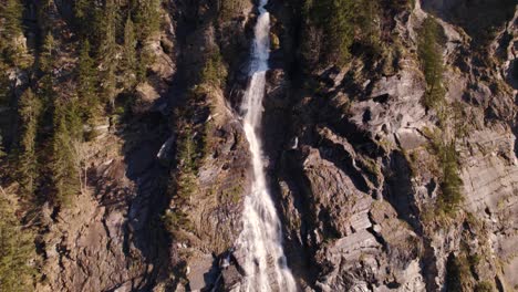 aerial drone footage panning down a picturesque waterfall in grindelwald in the swiss alps