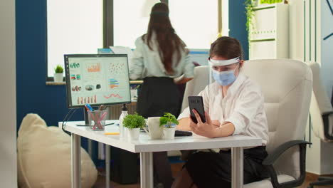 woman with visor using phone with wireless headphone for videocall