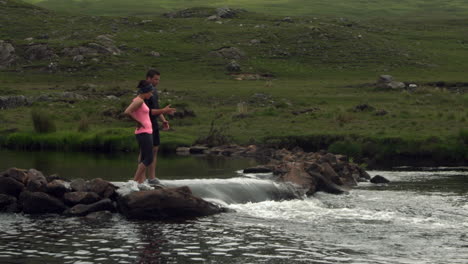 couple standing on rocks in the middle of a river