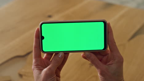 businesswoman arms holding mockup smartphone indoors. lady using green cellphone