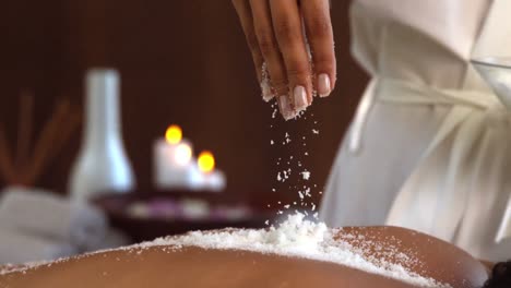 beauty therapist pouring salt scrub on back