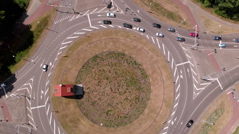 vista aérea de los pájaros arriba hacia abajo de una rotonda holandesa de doble carril con tráfico moderado dando vueltas, disparando girando junto con los automóviles