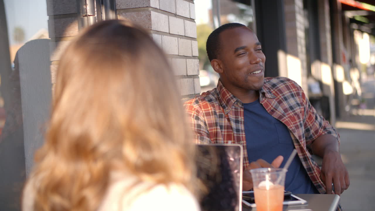 Mixed race couple talking at a table outside a coffee shop