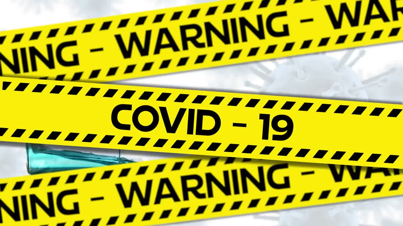 Words Warning Covid-19 written in black letters on yellow and black tape with Covid-19 spreading