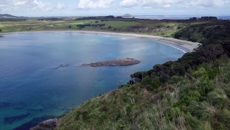 drone-shot-flying-over-a-ridge-and-exposing-Maitai-Bay-beach-at-Karikari-Penisula-in-New-Zealand