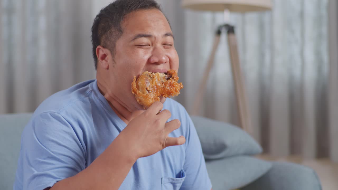 집의 거실 소파에 긴 을 먹고 패스트푸드를 먹는 한 아시아인 남자