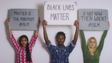 3 junge leute, die black lives matter-schilder hochhalten