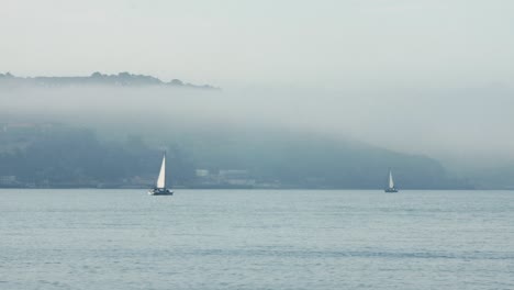 sailing boats middle of blue river in foggy scene, lisbon city, portugal