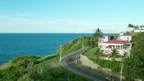 bird's eye view of tourist boogies taking a curve in búzios, brazil