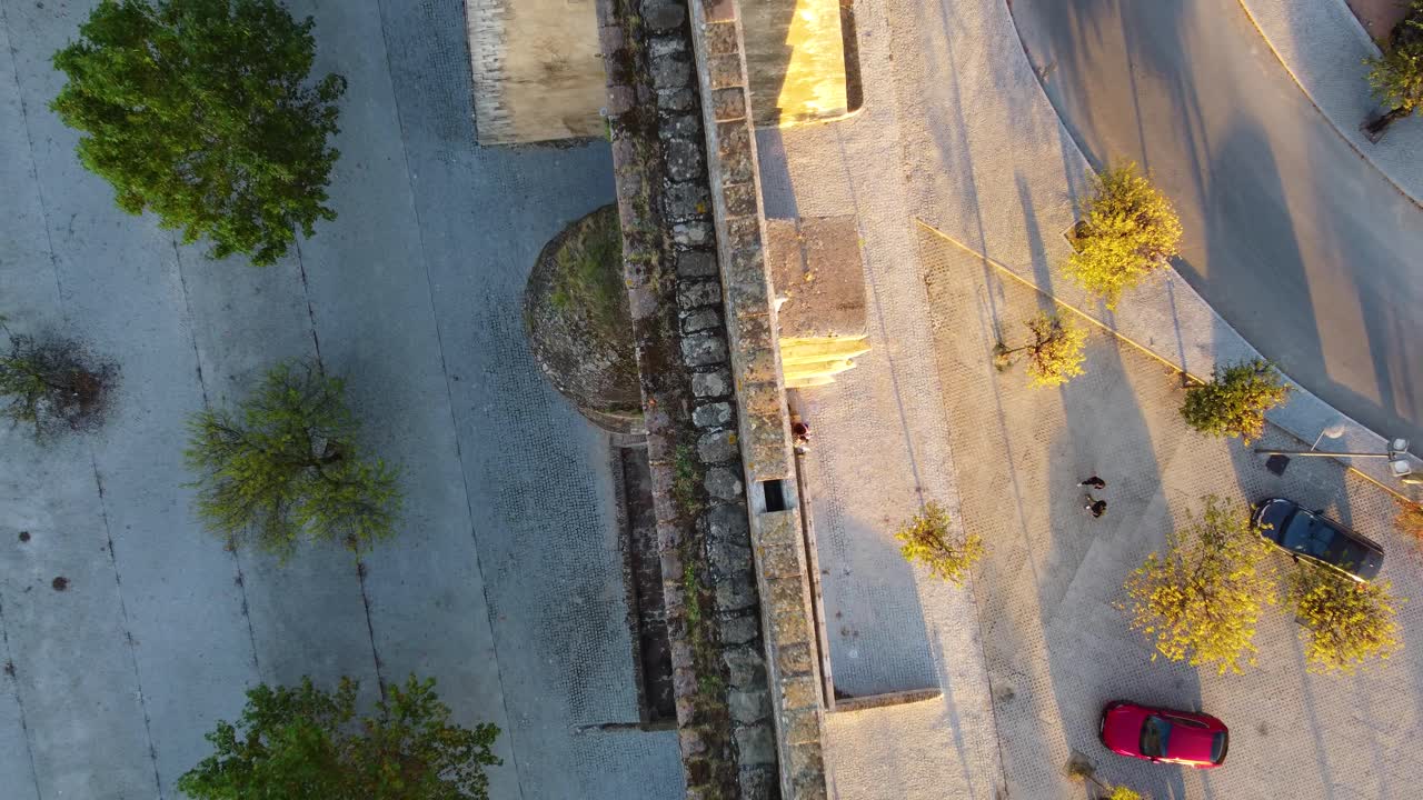 A stylistic shot of an aqueduct from above with the light of a sunset on one side and shadow on the other