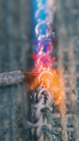 cu: skilled goldsmith welds long gold chain with gas burner and special tool on asbestos cover extreme close view