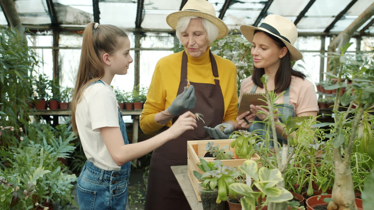 Grandmother, daughter, and granddaughter learning about plants in a greenhouse