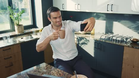 Business-man-making-selfie-photo-in-kitchen.-Topdown-portrait-of-smiling-man