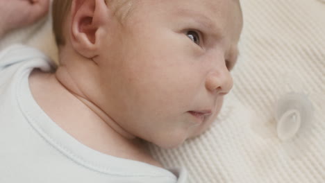 close up of a cute newborn baby lying on bed and moving