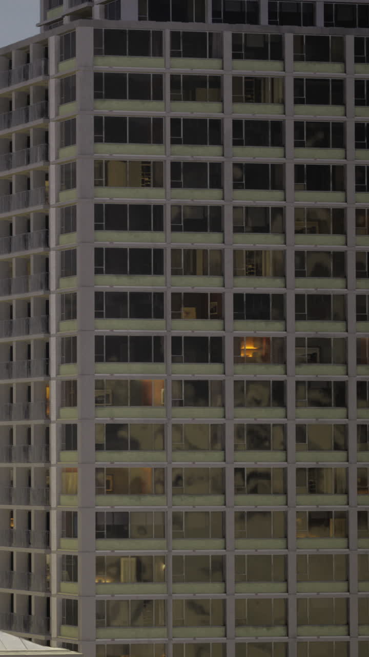 Atardecer urbano con luces cálidas iluminando las ventanas de los apartamentos.