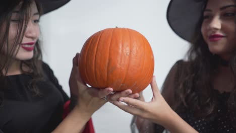 Two Witches Holding a Pumpkin