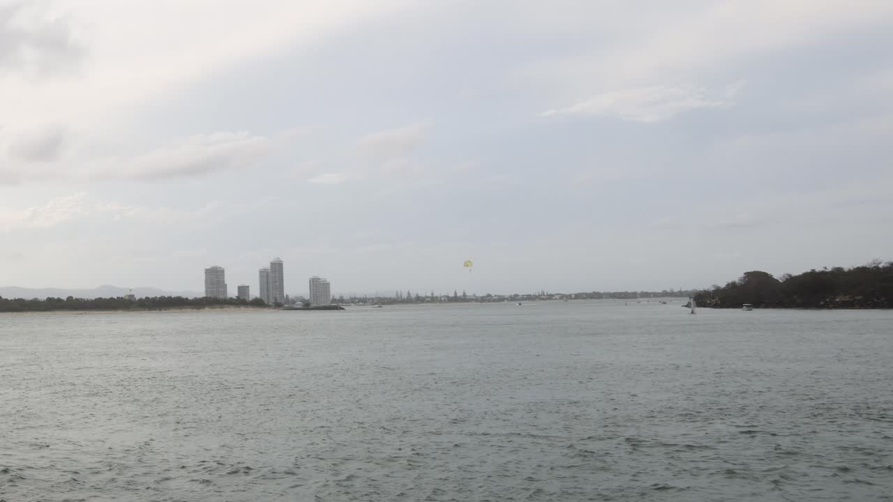 도시 스카이라인 근처의 수로를 가로질러 보트가 움직입니다.