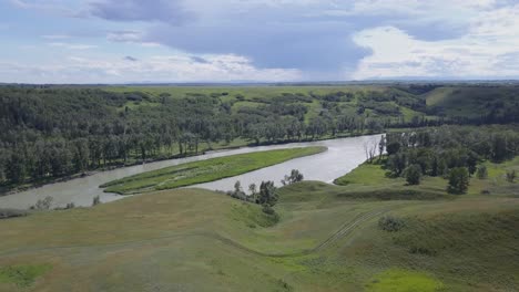 irregular grassy hillside leads down to the slow flowing river