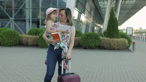 mother and daughter near airport. woman hold passports and tickets in hand. child and mom vacation