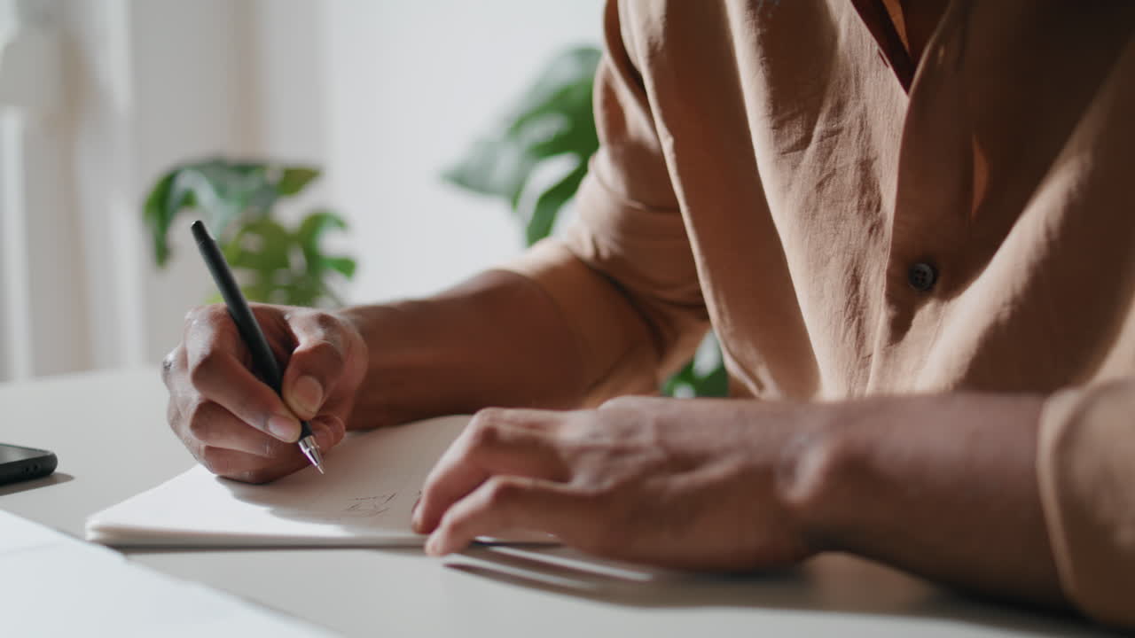Man hands writing notebook closeup. Unrecognizable guy making notes at home