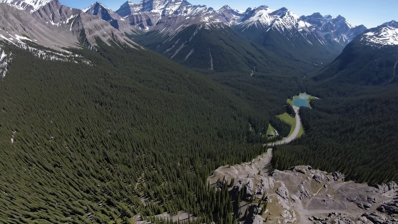 Aerial video captures a breathtaking mountain landscape with snow-capped peaks and dense forests