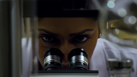 scientist looking through a microscope in a lab