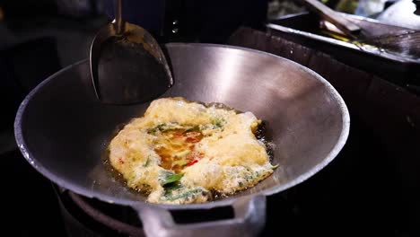 cocinando una tortilla en un puesto de comida callejera
