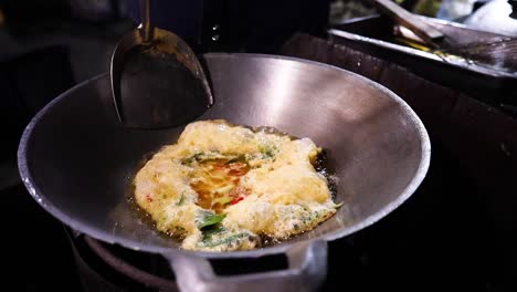 cooking an omelet in a street food stall