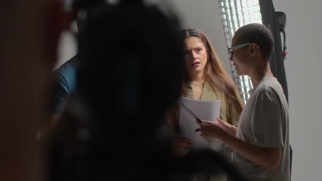 director de cine hablando con actores masculinos y femeninos sosteniendo guiones ensayando para filmar una película o video en el estudio 3