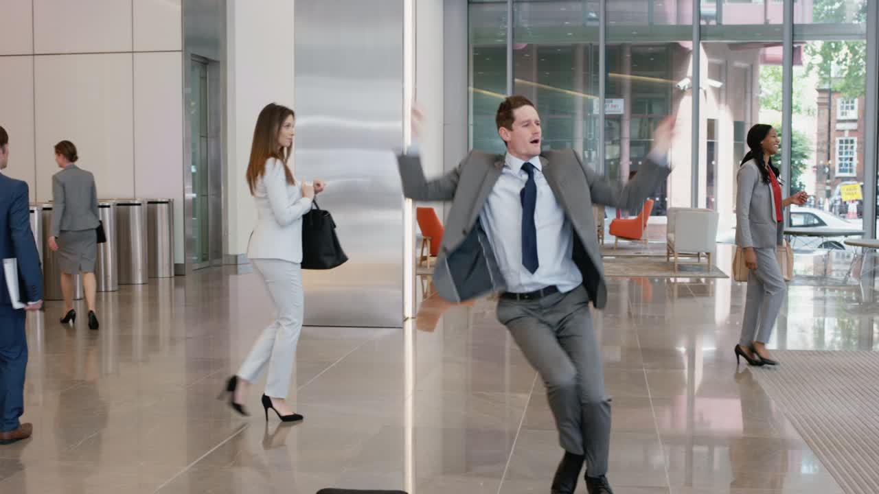 Metraje de video 4K de un empresario bailando en el vestíbulo del trabajo