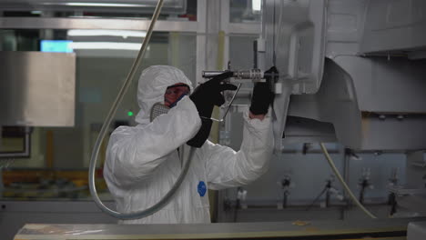 worker performing car body painting or maintenance in a factory