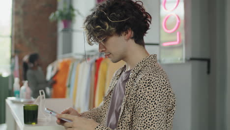 young man using smartphone in clothes shop