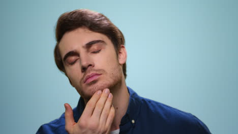 Handsome-man-checking-beard-in-studio.-Bearded-guy-posing-on-blue-background