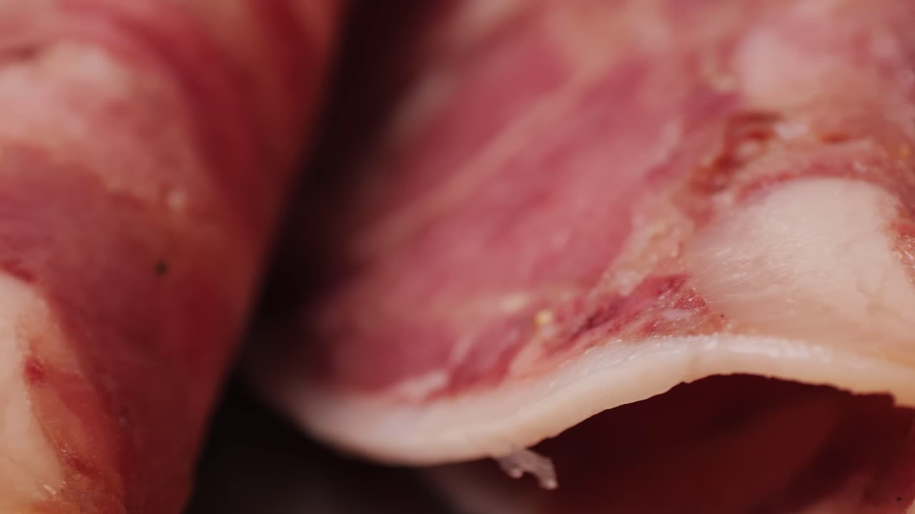 black bull sausage ham, tongue pork dry-cured sausage on a black background, traditional spanish delicatessen food, close up.