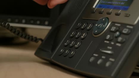 a close up of a hand picking up and dialing an office phone then hanging up