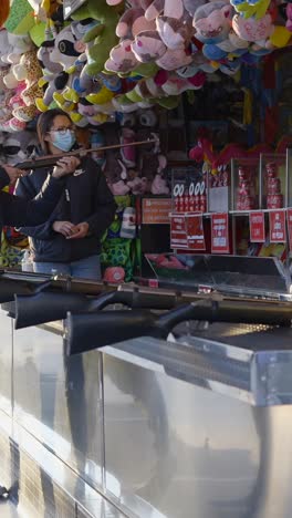 person playing a shooting game at a carnival with stuffed animal prizes