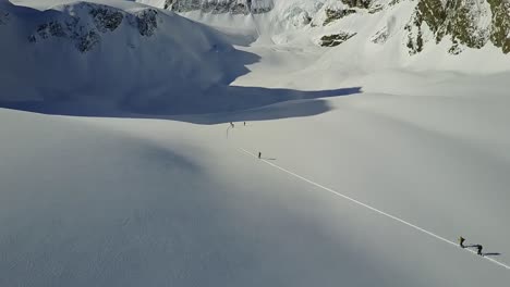 drone passing over backcountry skiers as they ascend skintrack in remote mountains