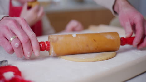 dad helps son roll out dough for gingerbread cookies