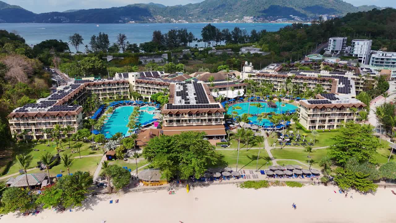 Drone footage showcasing a luxury resort in Phuket, Thailand, highlighting pools, lush greenery, and beachfront views under bright daylight