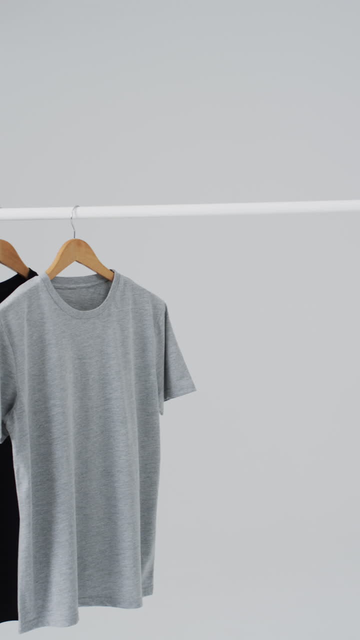 Vertical video of t shirts on hangers and copy space on white background