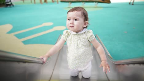 half ukrainian-korean baby girl climb on slide at public playground. - close up, slow motion