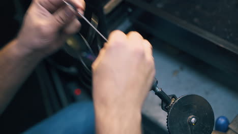 joyero bobinas de alambre de oro en alfiler de metal en el lugar de trabajo de cerca